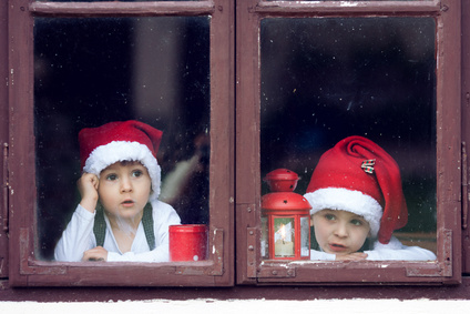 Two cute boys, looking through a window, waiting for Santa